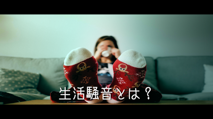 隣の部屋からの騒音に悩んでいる女性の画像 ソファーに座り足を机の上に置き、コーヒーを飲んでいる